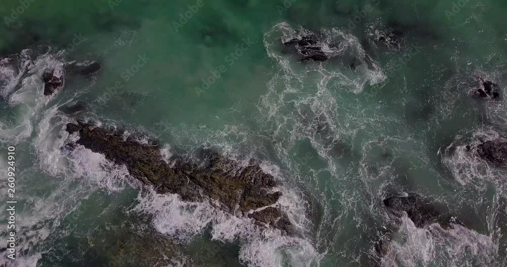 Rising top down shot of waves breaking over rocks Rising top down shot of waves breaking over rocks