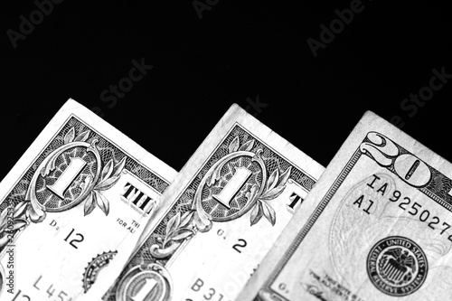One and twenty dollar bills on a dark background close up in monochrome