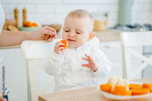 baby eating carrots in the kitchen at the table