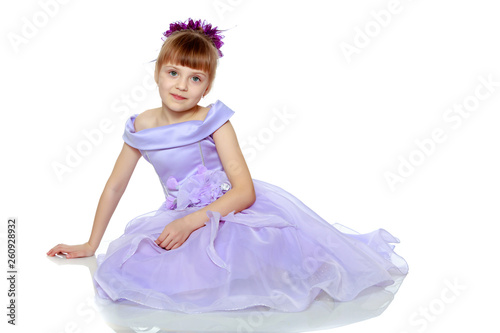 Girl sits on the floor with her hands folded in front of her.