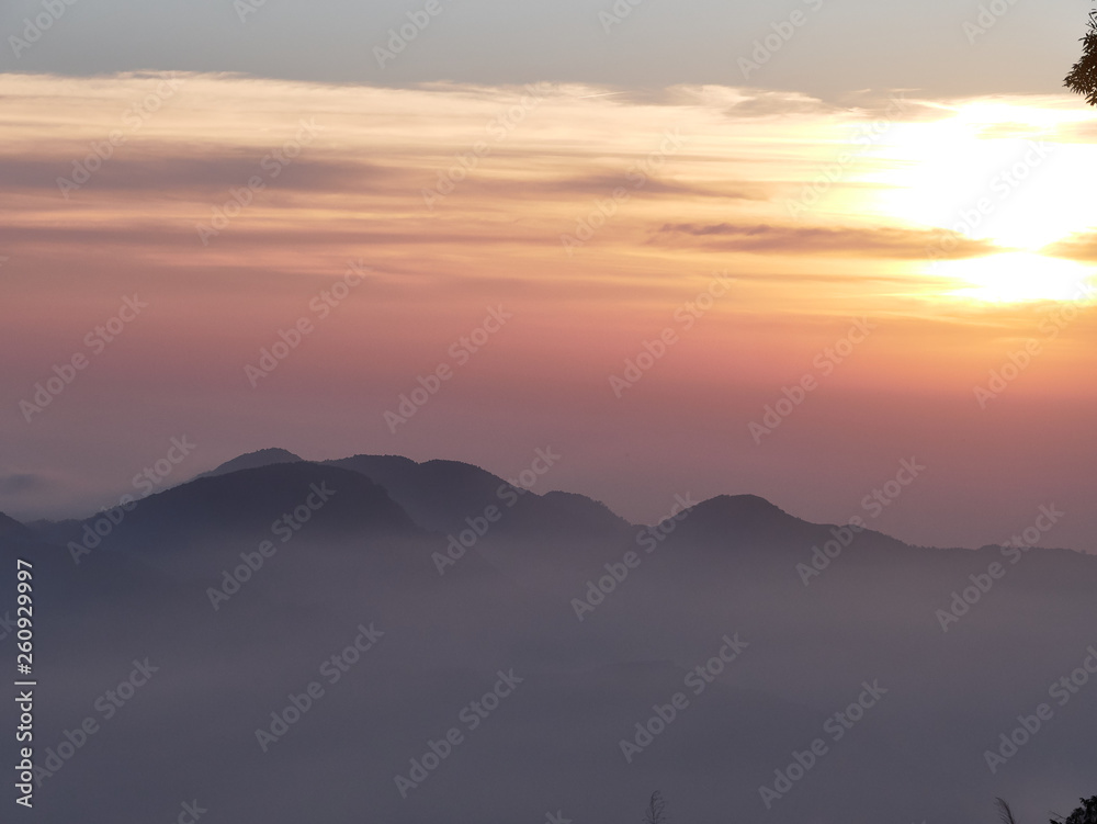 Sun set in Taiwans mountain region - Alishan mountain sun set in warm pastel colors with fog between mountain ranges Sun set in Taiwans mountain region - Alishan mountain sun set in warm pastel colors with fog between mountain ranges