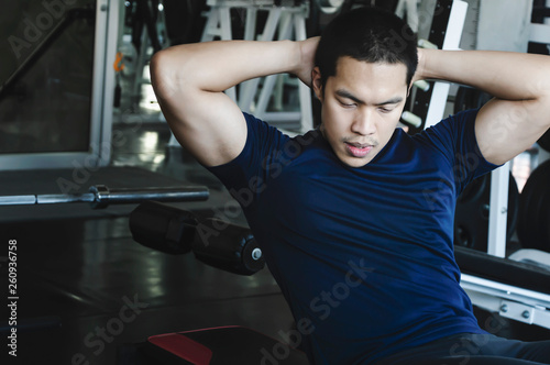 Young man doing sit-ups on the bench.