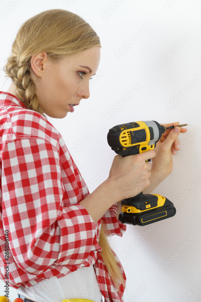 Woman drilling in wall Woman drilling in wall