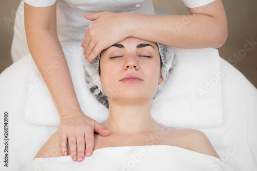 Beautician makes a professional massage of the face of the neck and shoulders for a young girl in the Spa salon. The view from the top. Facial beauty treatment