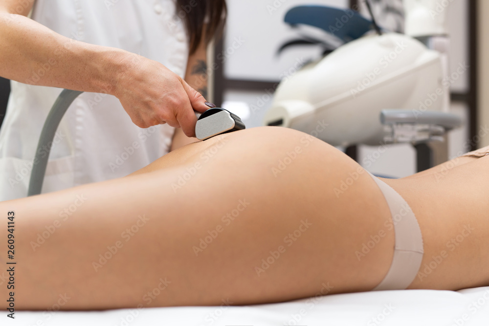 Close-up of a woman masseur doing a vacuum massage of the buttocks for a young woman. Cosmetology, body and skin care. Vacuum roller massage with the possibility of ultrasonic action.