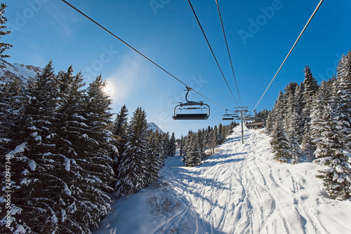Traveling up an alpine mountainside on ski chair lift © Paul Vinten