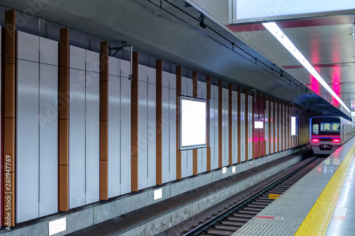 Train running on platform station with billboard on wall