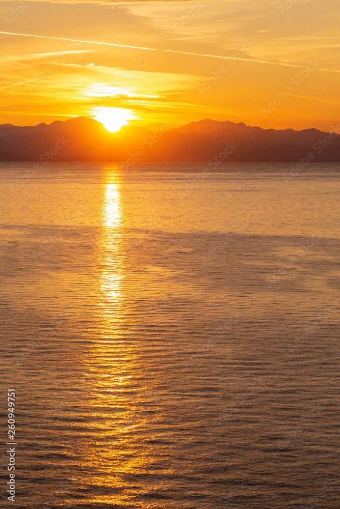 Summer sunrise on coast, Corfu island, Greece. Beach with perfect views of the mainland Greece mountains.