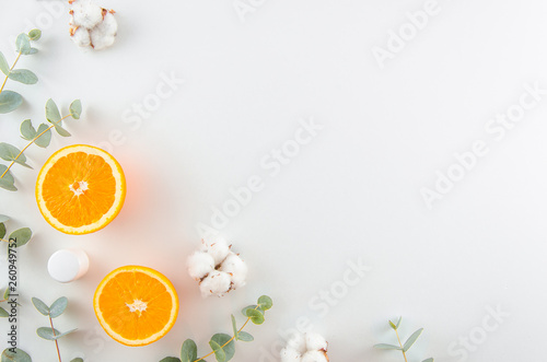 Flat lay home made cosmetics concept. Corner frame with green eucalyptus ,oranges, cotton flowers and cosmetic jar. Top view mockup. Minimal natural eco friendly design