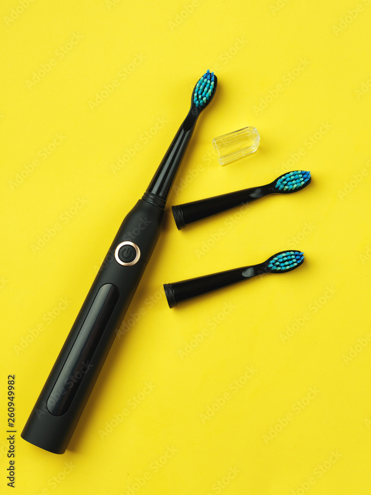 Electric toothbrush on yellow background with copyspace