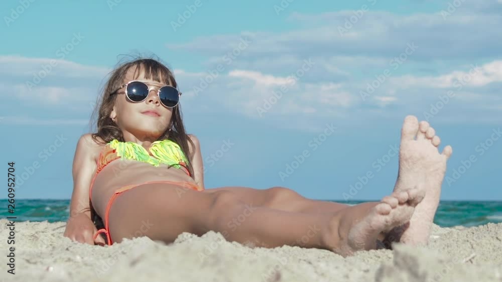 Child on the beach in sunglasses. Cute little girls in bikini and