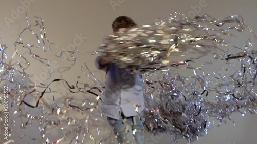 Slow motion of teenager spinning around and throwing up frippery.