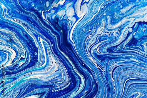 Hand painted background with mixed liquid blue, white, yellow paints. Abstract fluid acrylic painting. Applicable for packaging, invitation, textile, wallpaper, design of different surfaces