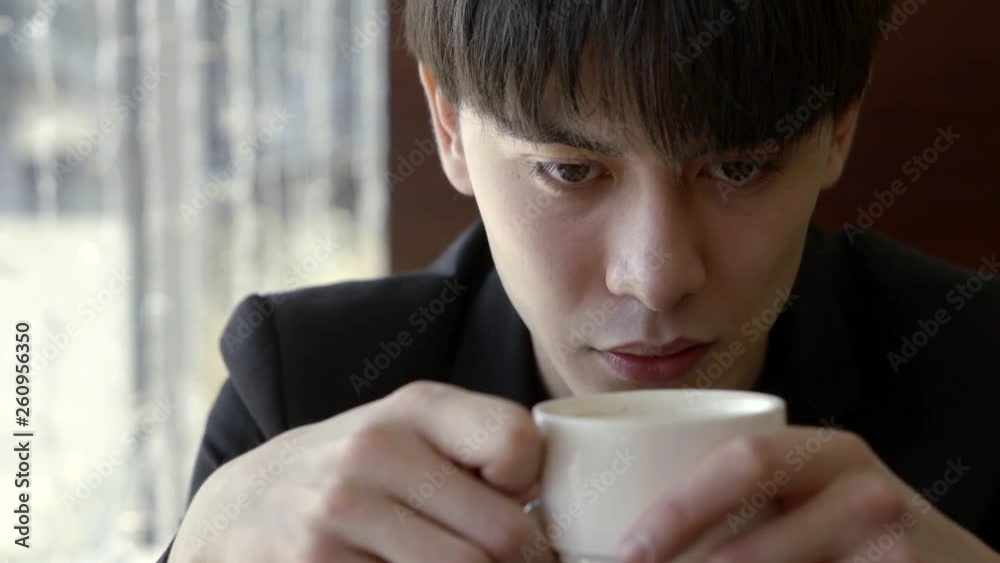 Portrait of a young confident Asian man, thoughtful thinking in a cafe by the window with a Cup of invigorating morning coffee Portrait of a young confident Asian man, thoughtful thinking in a cafe by the window with a Cup of invigorating morning coffee
