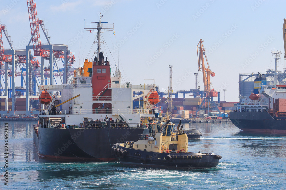 Tugboat at the bow of cargo ship , assisting the vessel to maneuver in Sea Port of Odessa, Ukraine