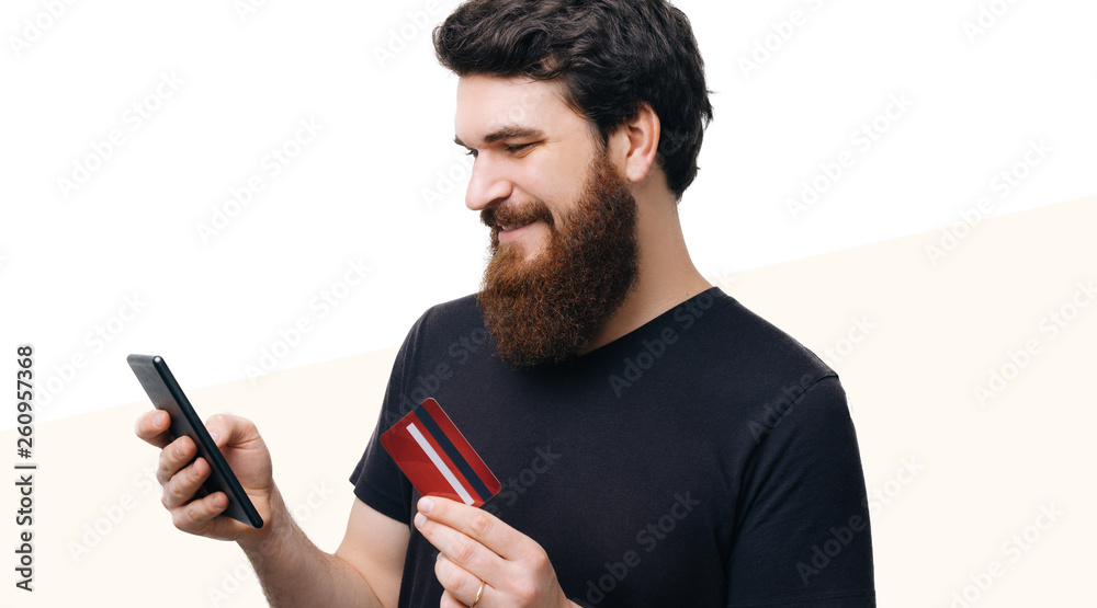 Poartait of handsome man, using mobile and holding credit card over white isolated background Poartait of handsome man, using mobile and holding credit card over white isolated background