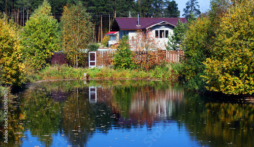 Wooden house with meadow in front of it standing near river. 