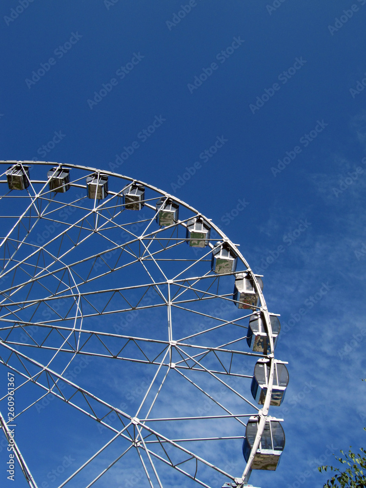 Ferris wheel in an amusement park on a sunny summer day with blue sky and almost no clouds. Ferris wheel in an amusement park on a sunny summer day with blue sky and almost no clouds.