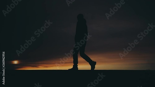 lonely man walking alone on the horizon line at sunset