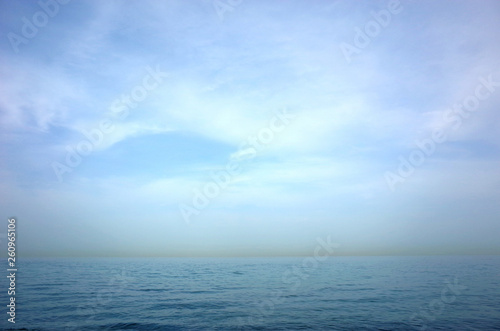 Blue seascape of Gulf of Oman seen from Arabian peninsula with yellow line of sandstorm over Iran