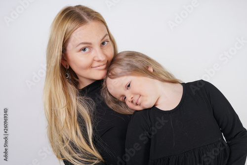 cute kind caucasian blonde mom and daughter posing on white background. a parent and a child experience love and hug.