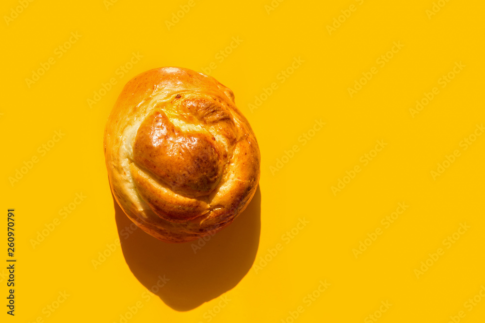 Fresh home baked artisan Easter sweet bread bun on bright yellow background. Trendy style with harsh light hard shadows. Coffee pastry. Holiday baking breakfast morning. Recipe cafe menu template Fresh home baked artisan Easter sweet bread bun on bright yellow background. Trendy style with harsh light hard shadows. Coffee pastry. Holiday baking breakfast morning. Recipe cafe menu template