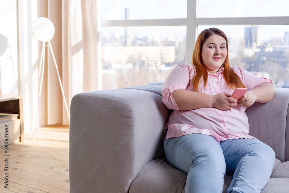 Delighted nice plump woman holding her smartphone Delighted nice plump woman holding her smartphone