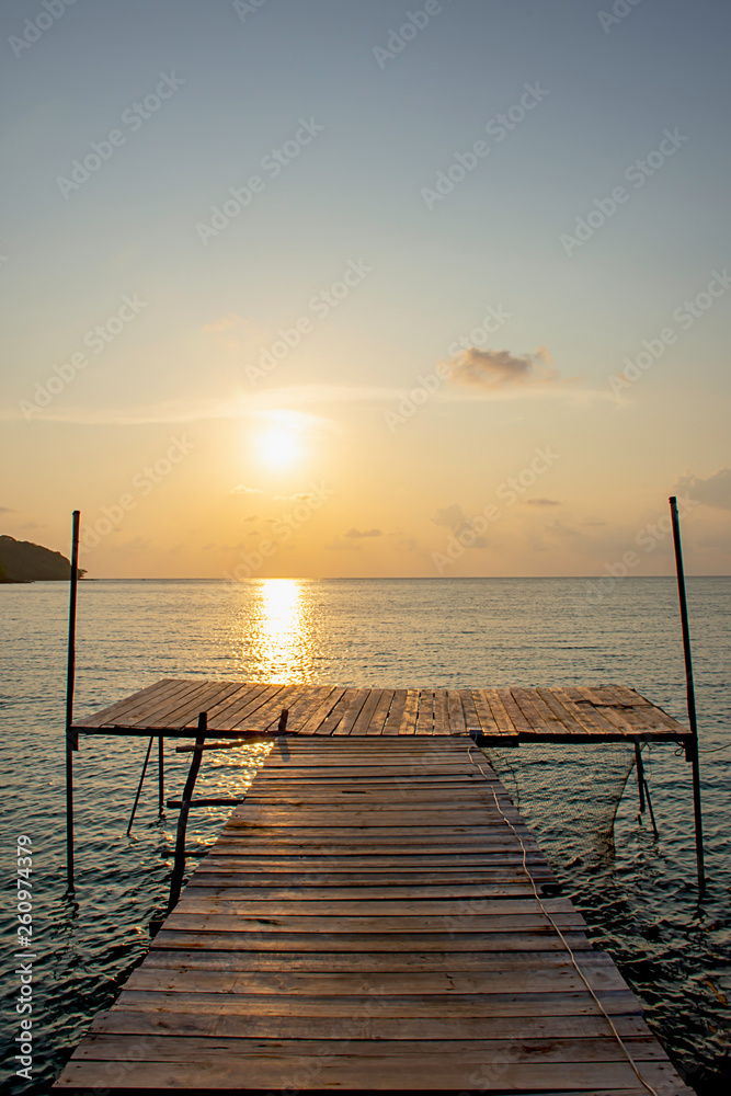 Wooden bridge in the sea and Golden reflections of the Sun