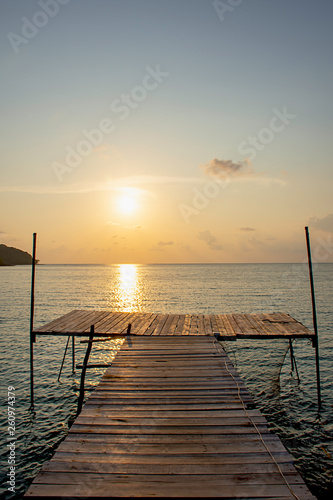 Wooden bridge in the sea and Golden reflections of the Sun