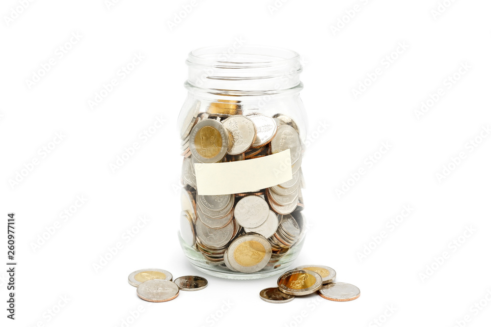 New Thai Baht coins in a glass jar with blank label, isolated on white background. Business and finance concept. New Thai Baht coins in a glass jar with blank label, isolated on white background. Business and finance concept.