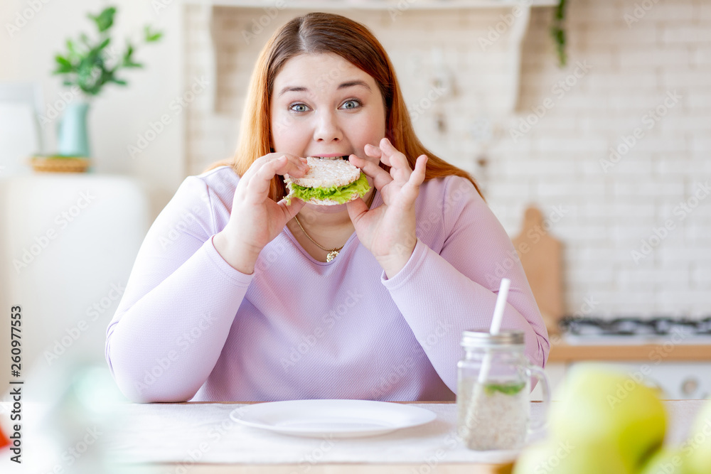 Hungry chubby woman biting a tasty sandwich Hungry chubby woman biting a tasty sandwich
