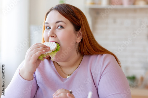 Pleasant plump woman eating a healthy sandwich