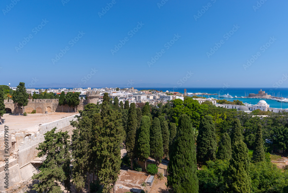 View from the walls of the Palace of the Grand Master of the Knights of Rhodes (Kastello) over the old Mandraki harbour, the old city and the Saint Nicholas fort. Summer in Dodecanese islands, Greece.