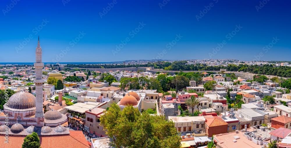 Panoramic view of the Rhodes medieval city surrounded by old stone walls, with the historic Suleiman Mosque on the left and the new town in background. Popular summer holiday destination in Greece.