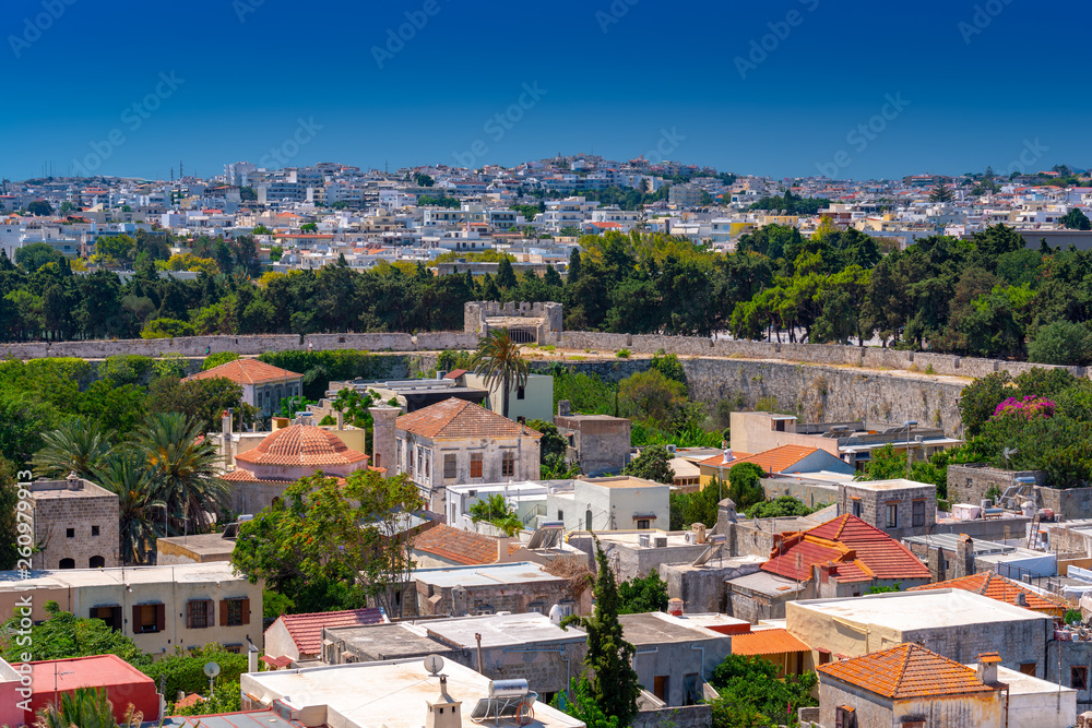 Panoramic view of the Rhodes medieval old city surrounded by ancient stone defensive walls, with the new town and Acropolis in the background. Popular summer holiday destination in the Greece.