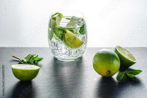 Glass of mojito cocktail on a dark board with fresh peppermint leaves and lime fruits  photo