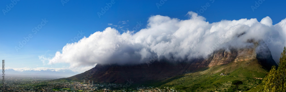Table Mountain under huge white cloud on blue sky background beautiful landscape panorama, scenery panoramic view of capital city at foot of mountain on sunny day in Cape Town South Africa, copy space