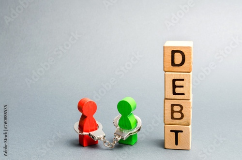 Foto Two people are bound by handcuffs with the word Debt