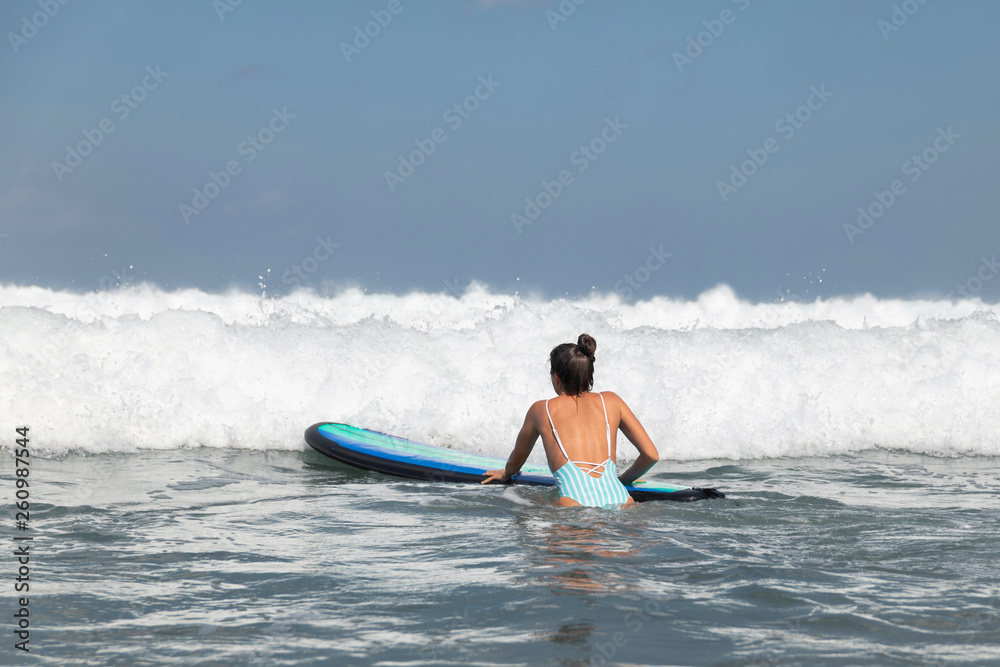Woman surfer is trying to get into line up trough waves during her surfing workout