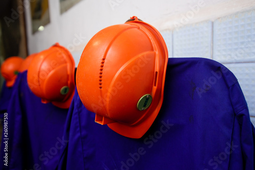 orange-colored mining helmets hang over protective gowns. Working uniform. photo