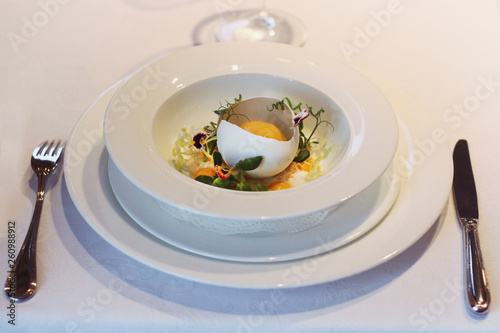restaurant dish served on a white tablecloth. foie gras with lettuce in eggshell