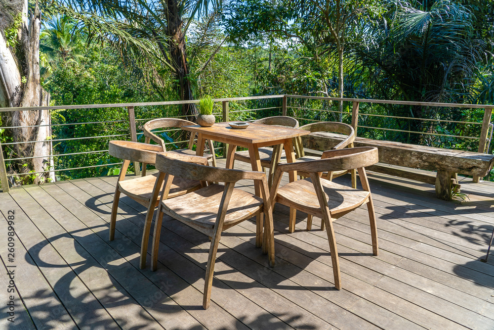 Wooden table and chairs in empty tropical cafe next to rice terraces in island Bali, Indonesia