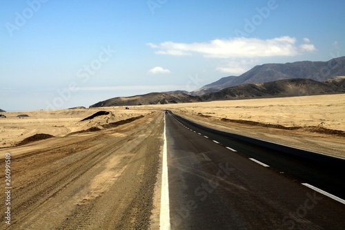Lonely asphalt road through barren waste land into endlessness of Atacama desert, Chile