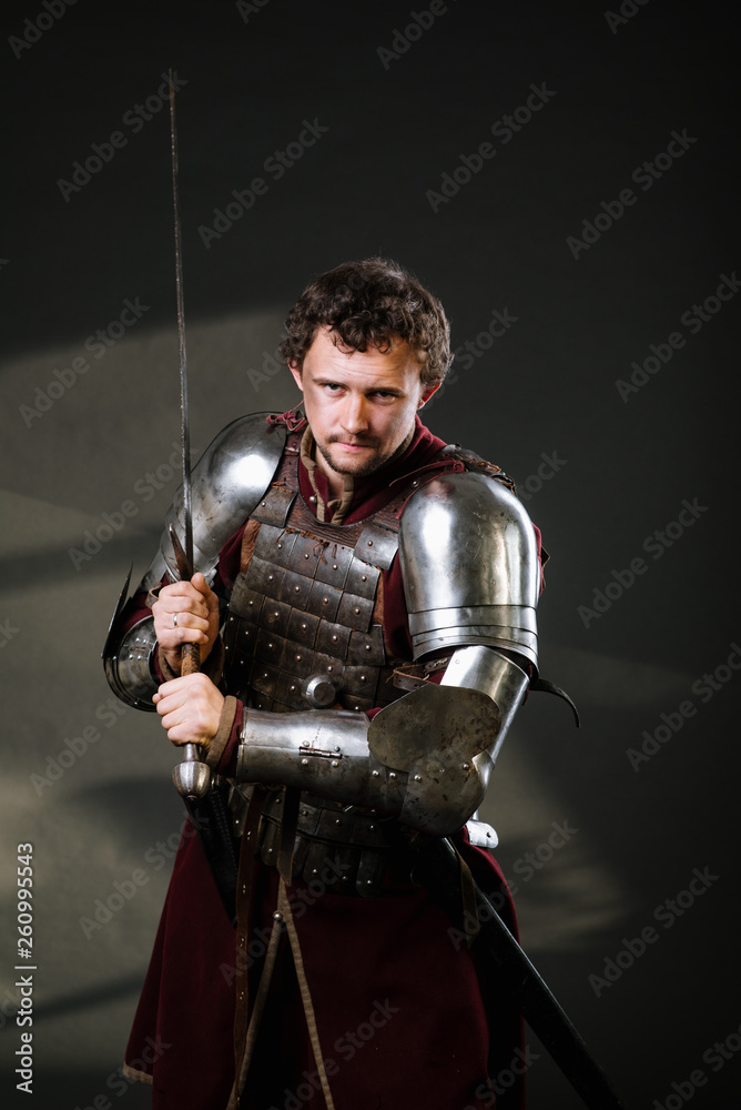 Medieval man knight in armor and weapon on dark background. Portrait of the knight Medieval man knight in armor and weapon on dark background. Portrait of the knight
