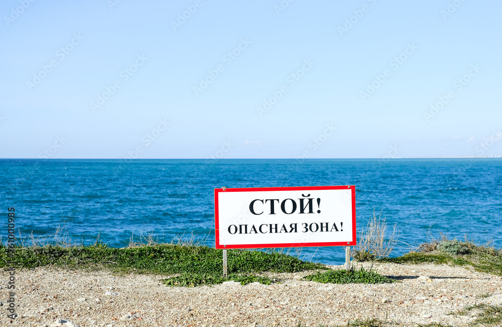 Warning sign on the background of the sea with the inscription 