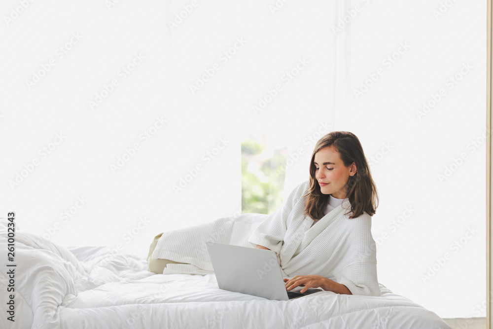 Woman typing work laptop on bed working in bedroom at home Woman typing work laptop on bed working in bedroom at home