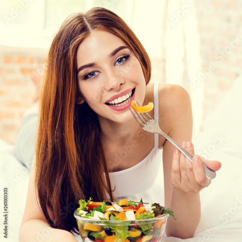 Beautiful young woman eating salad, indoor