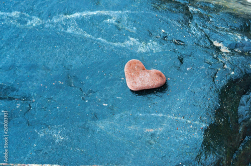 A heart-shaped sea rock on a dark background. A heart of red stone.
