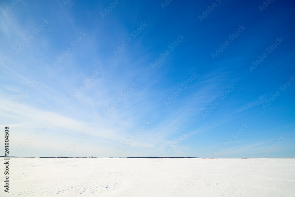Blue sky with white clouds over white snowy field in winter