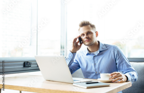 Stylish young man calling by the phone to solve business problems. Online consultation by phone. Freelancer discussing the development and planning of his online project. Outsourcing. Mobile services.